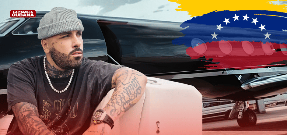 artista urbano Niky jam sentado en un mueble en la parte izquierda obserbando la bandera de venezuela que esta a la derecha y de fondo el jet pribado del artista pintado de negro.